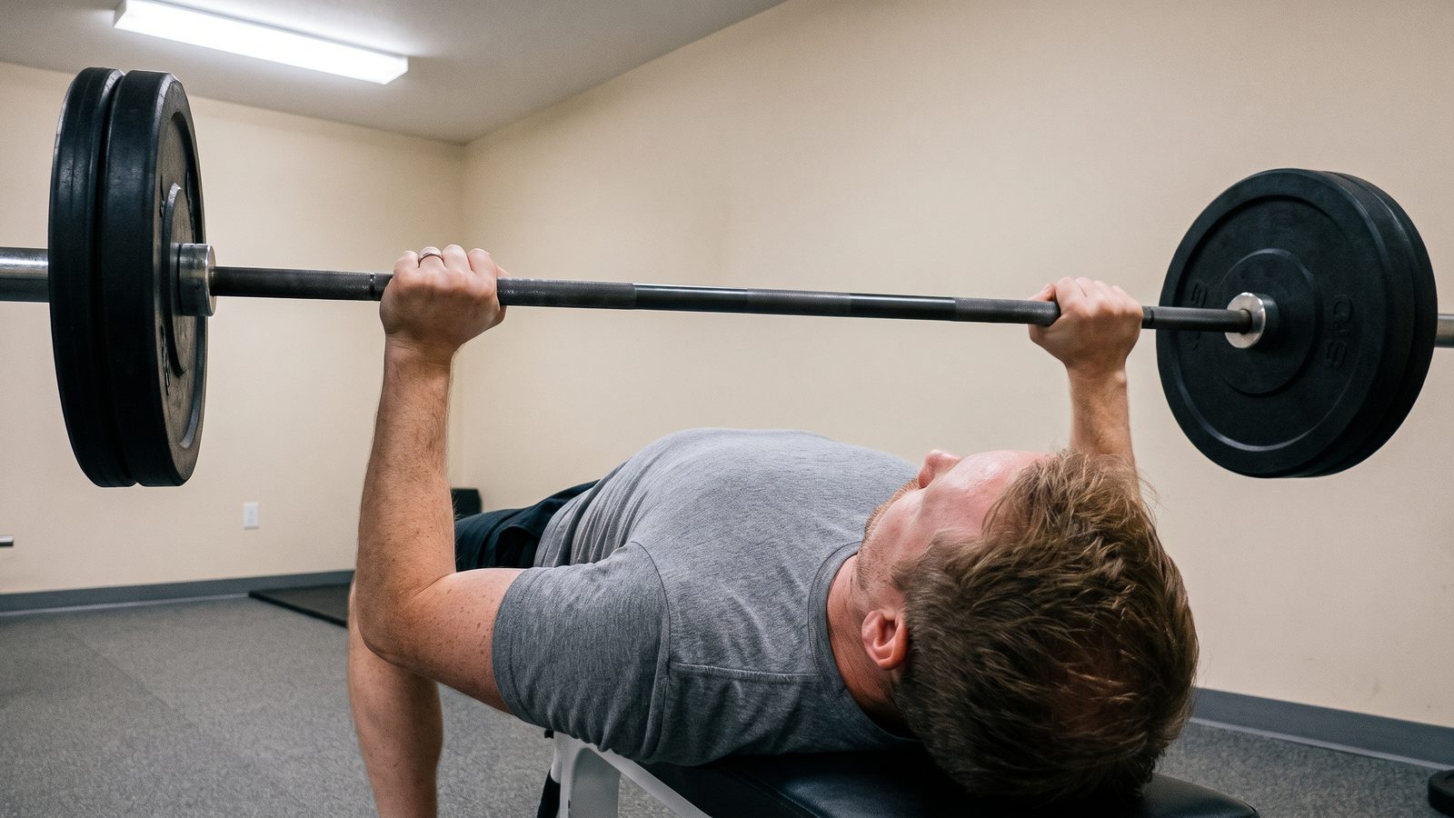 Close view of a lifter's hands set wide on a knurled barbell before a bench press