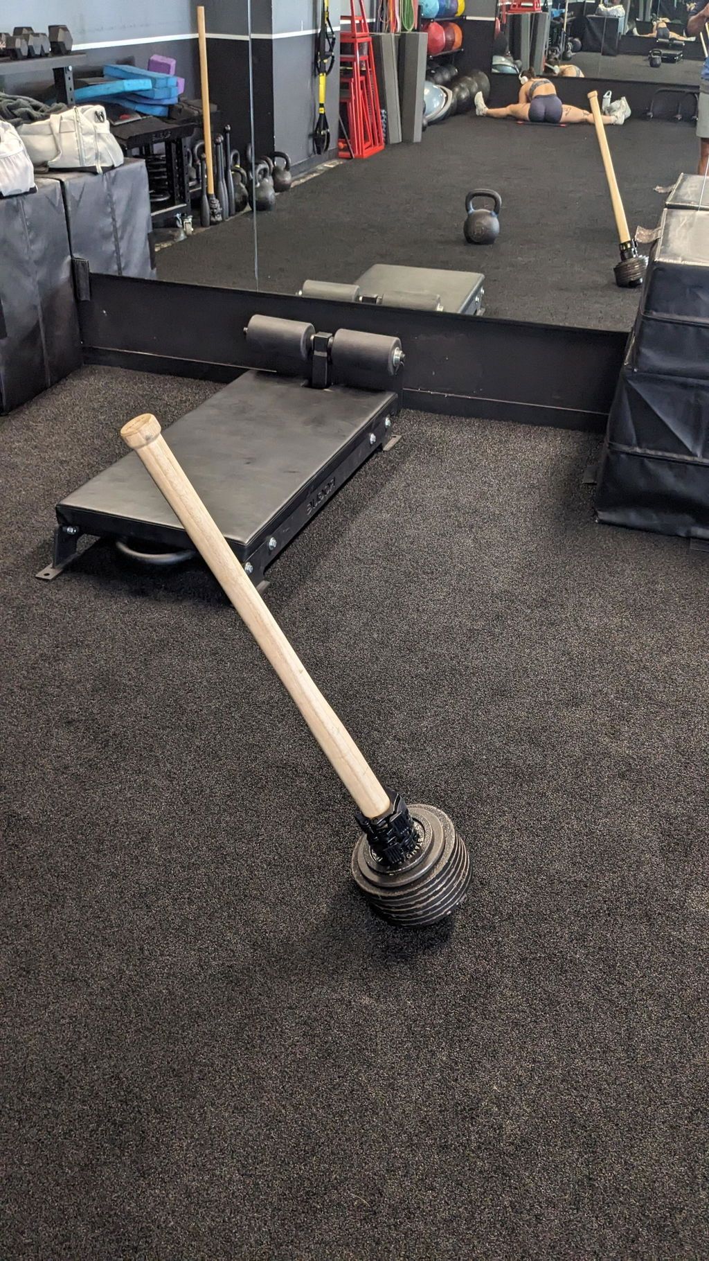 A buyer's phone photo of the wooden EZ-MACE PRO loaded with iron plates on a gym floor