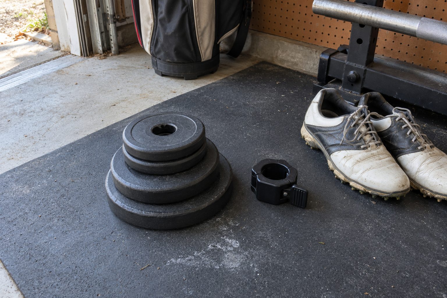 A small stack of old iron Olympic plates and a collar on the author's garage floor mat, next to his golf shoes