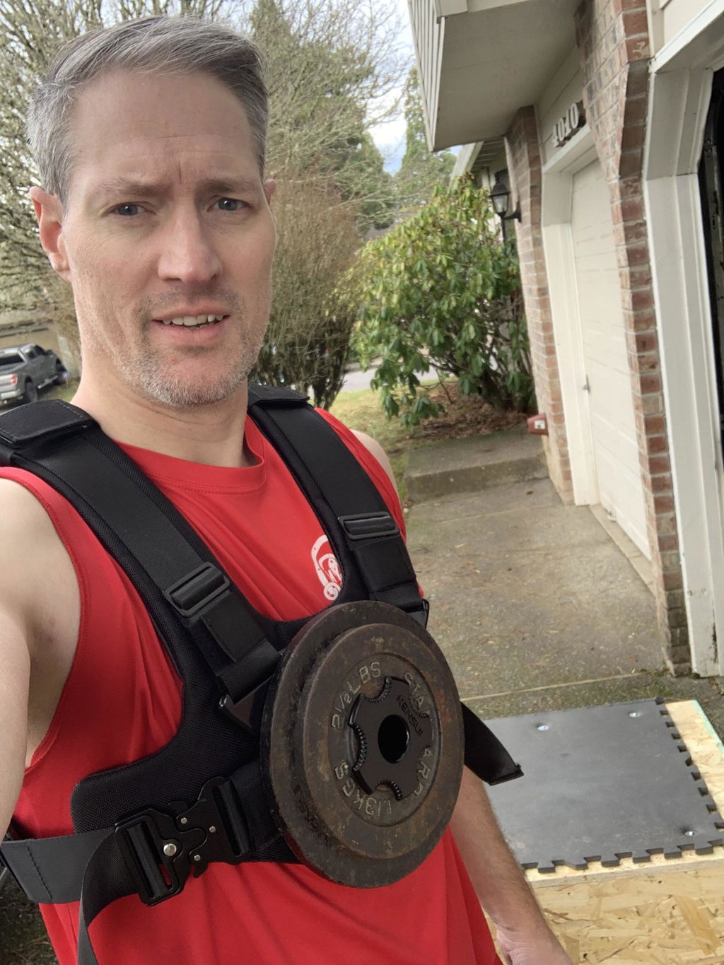 An owner in his driveway wearing the vest with a plate loaded on the chest post
