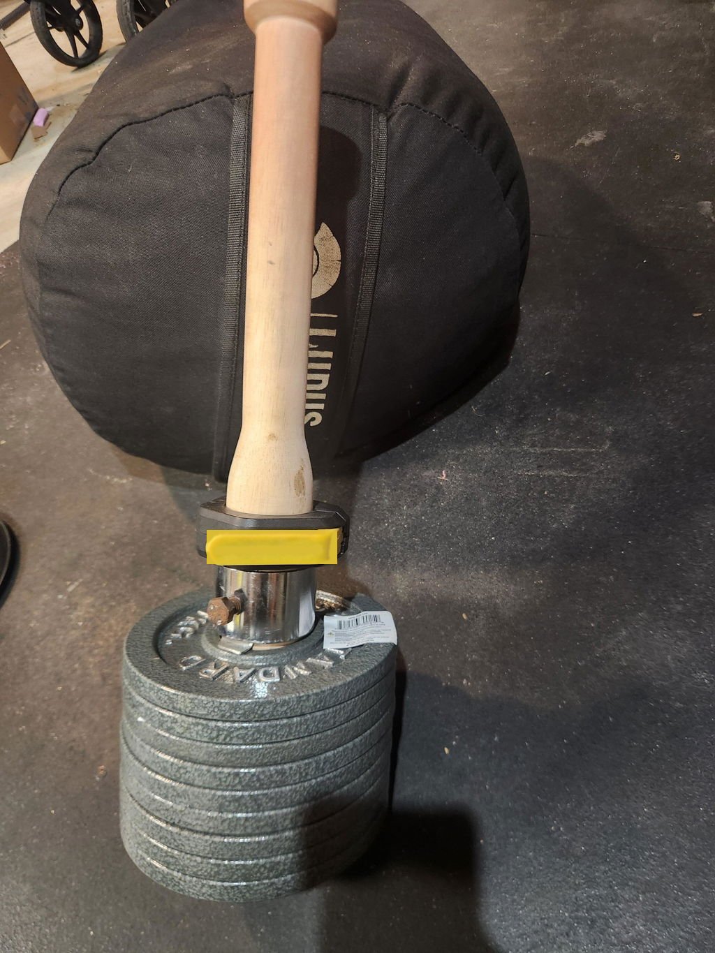 A buyer's phone photo of the wooden EZ-CLUB PRO loaded with a tall stack of plates, leaning on a heavy bag