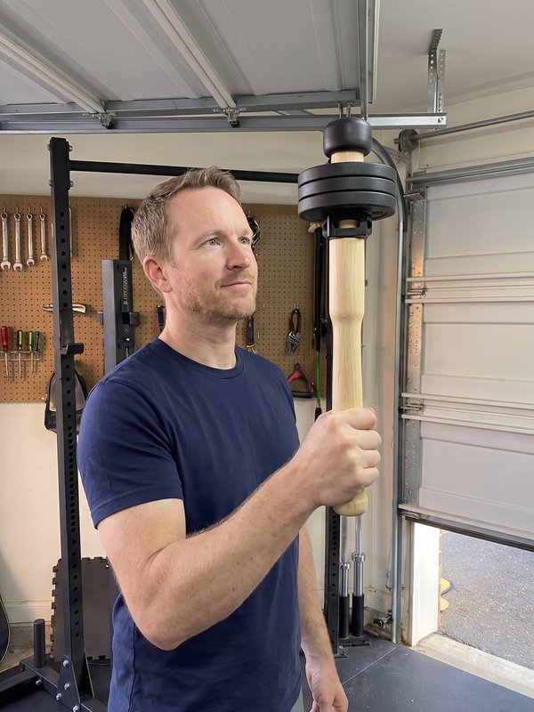 The author in his garage holding the wooden EZ-CLUB PRO upright, plates at the top