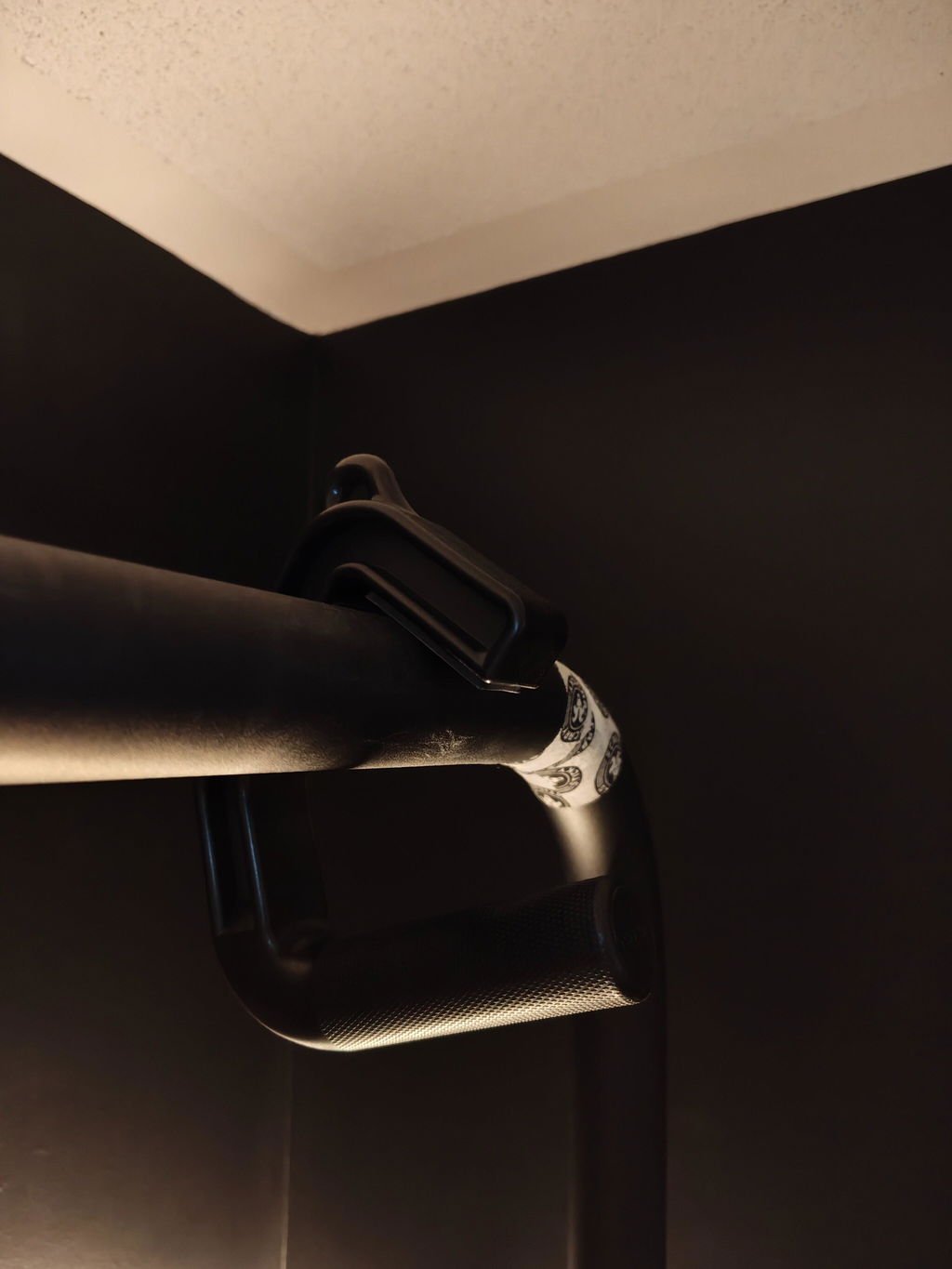 An owner photograph looking up at a ceiling mounted pull-up bar in a house, with a single black hooked handle in place on the bar